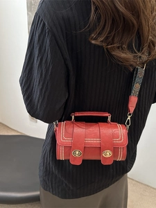 Red vintage cylindrical crossbody bag with ethnic embroidered strap on model