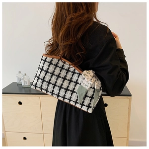Side view of a black and white tweed tote bag with brown trim and floral scarf detail