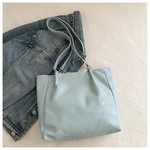 Detailed top view of a light blue bow tote bag with textured finish on a white background