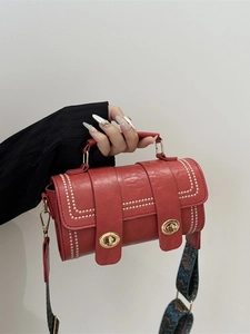 Red crossbody bag with gold studs and ethnic print wide strap in retro fashion style