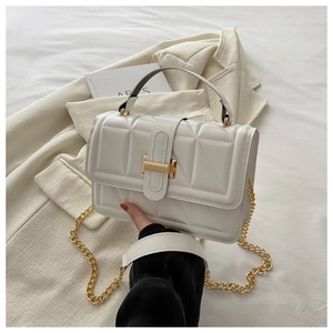 Close-up of white quilted leather handbag with gold metal clasp and chain strap detail