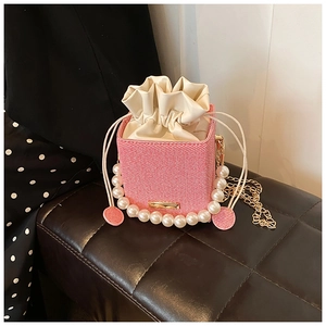 Vue détaillée du mini sac tressé rose avec poignée en perles et bandoulière en chaîne dorée