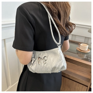 Silver pleated underarm bag with metallic bow detail shown on model in stylish setting