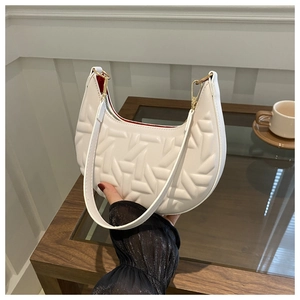 Detail view of white hobo bag with geometric quilted texture and contrast red lining