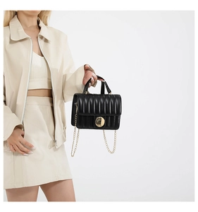 Detailed view of the black quilted texture with gold round metal lock on the flap bag