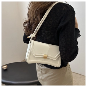 Detail of white saddle bag showing gold buckle and stylish knotted shoulder strap