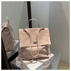 Close-up of light pink textured nylon backpack with a silver metal twist lock closure
