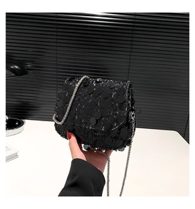 Close-up of black sequined crossbody bag with silver chain strap and shimmering texture