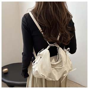 Detail view of stylish beige bow backpack showing size and scale on a female model