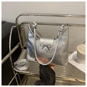Détail du sac argenté métallisé à texture plissée avec un nœud chromé élégant