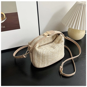 Detail of beige straw crossbody bag with golden metal clasp and leather strap