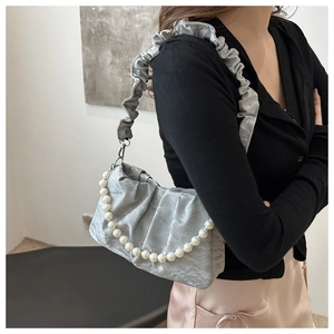 Close-up of light gray pleated shoulder bag with elegant large white pearl chain detail