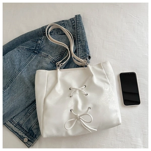 Close-up of white pearlescent PU leather tote bag with stylish bow tie detailing