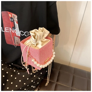 Detail of pink woven texture crossbody bag with pearl handle and golden chain strap