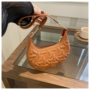 Detail view of brown embossed faux leather underarm bag with gold metal clasp