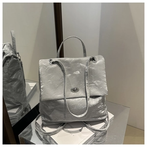 Detail of silver pleated texture backpack with metallic twist lock and top handle grip