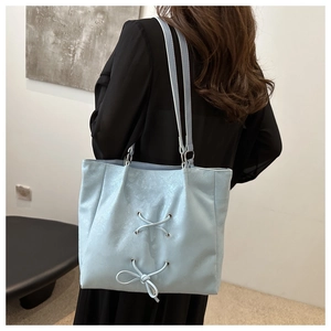 Rear view of a light blue tote bag with ribbon bow detail worn by a model