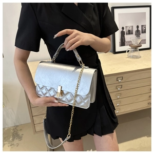 Detail einer silbernen Metallic-Stepptasche mit goldenem Drehverschluss und Kette