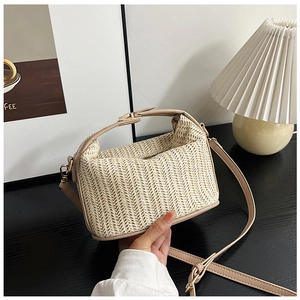 Detail view of woven straw crossbody bag with faux leather handles and gold metal hardware