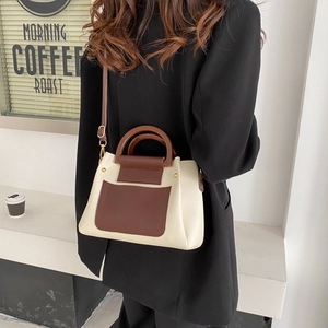 Chic two-tone square crossbody bag with wooden handle and gold hardware on a casual cafe background