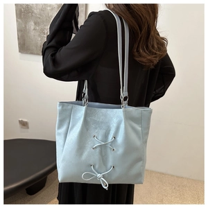 Light blue bow tote bag with pearlescent texture worn by a model in a minimalist setting