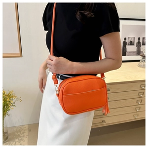 Dettaglio borsa a tracolla arancione texture litchi con nappa e finiture dorate