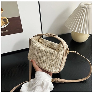 Detail of hand-woven straw crossbody bag featuring beige herringbone pattern and gold metal hardware
