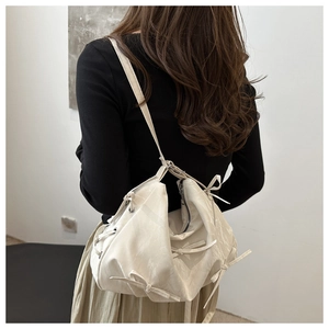 Detail showing beige bow knot shoulder bag with metallic eyelets on silky fabric