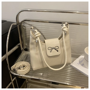 Détail d'un sac à bandoulière blanc crème avec boucle en métal et bandoulière nouée