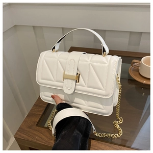 Detail of white quilted handbag with golden H-buckle and elegant chain shoulder strap