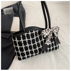 Detail of checkered tote bag with leopard bow ribbon against a business suit backdrop