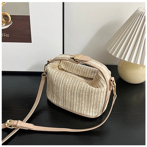 Detail of beige straw crossbody bag with leather trim and gold metal buckle closure