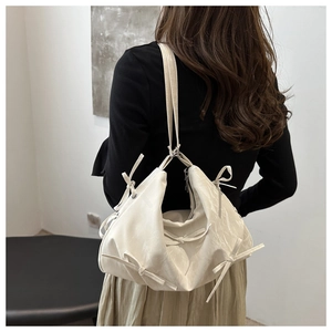 Chic white shoulder bag with bow accents worn by model to show size and fit