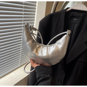 Detailed view of a silver croissant bag with quilted texture and sleek metal finish