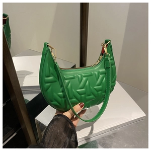Detail of green hobo bag featuring geometric quilted texture and red lining