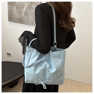 Detailed view of light blue tote bag with bow ties shown on model for size perspective