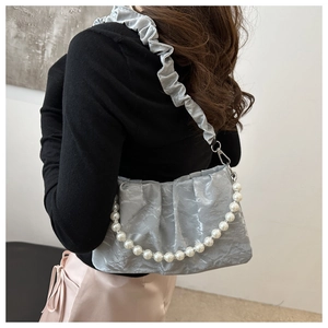 Detail of silver pleated cloud bag featuring pearl chain and ruffled shoulder strap
