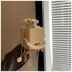 Détail du sac carré tissé avec poignée en perles et bandoulière chaîne dorée