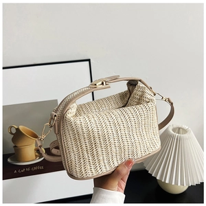Detail of beige straw crossbody bag with leather trim and gold metal clasp lock