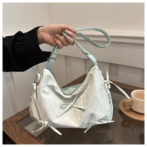 Detail of mint green ruched shoulder bag featuring sweet bow accents and textured fabric