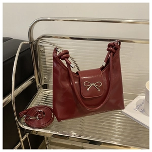 Détail du sac à bandoulière en cuir verni bordeaux avec boucle nœud argenté et poignée
