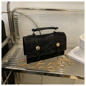 Detail of black crossbody bag featuring unique crinkled texture and gold chain strap