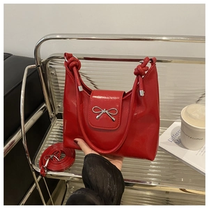 Détail du sac à main en cuir verni rouge vif avec nœud argenté et poignée nouée