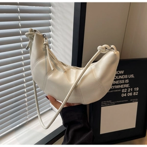 Detailed macro shot of the textured cream croissant bag showing stitching and knot details