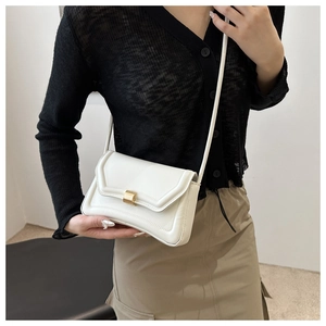 Detailed close-up of a white leather crossbody bag featuring a classic gold rectangular clasp