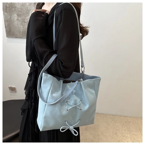 Detail of light blue tote bag featuring cross lace-up design and shimmering leather finish