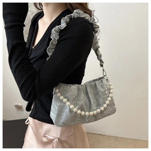 Close-up of gray pleated cloud bag featuring an elegant pearl chain strap detail