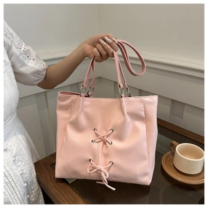 Detailed view of pink bow tote bag with metallic eyelets and crisscross strap design