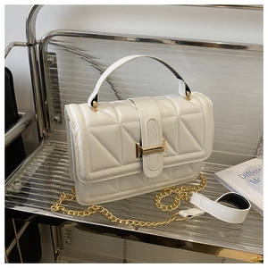 Detail of white quilted handbag showing textured geometric patterns and gold metal clasp