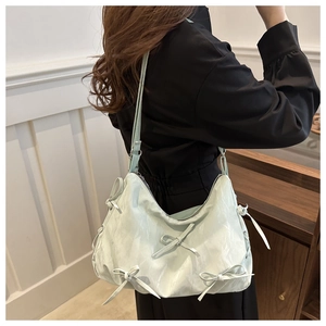 Détail du sac hobo vert menthe avec nœuds 3D décoratifs et texture de cuir plissé